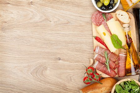 Cheese, prosciutto, bread, vegetables and spices. Over wooden table background with copy space Stock Photo - Budget Royalty-Free & Subscription, Code: 400-07481820