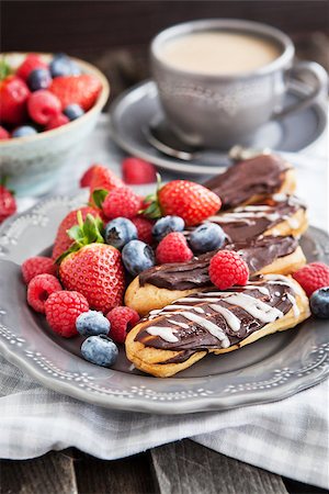 simsearch:400-07621036,k - Chocolate eclairs and fresh berries on plate with cup of coffee on the background Photographie de stock - Aubaine LD & Abonnement, Code: 400-07482294