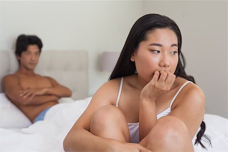 Boyfriend looking at upset girlfriend sitting on end of bed at home in bedroom Stock Photo - Budget Royalty-Free & Subscription, Code: 400-07483077