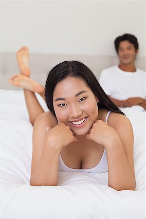 simsearch:400-07483522,k - Woman lying on bed smiling at camera at home in bedroom Stock Photo - Budget Royalty-Free & Subscription, Code: 400-07483090