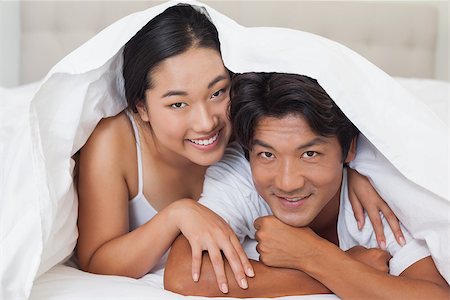 simsearch:400-07483522,k - Happy couple lying on bed together under the duvet at home in bedroom Stock Photo - Budget Royalty-Free & Subscription, Code: 400-07483114