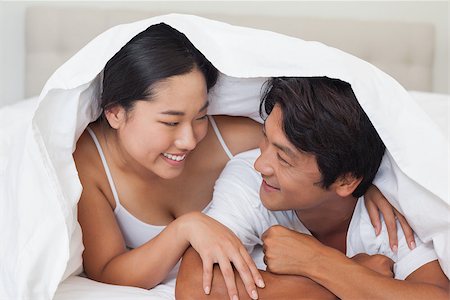 simsearch:400-07483522,k - Happy couple lying on bed together under the duvet at home in bedroom Stock Photo - Budget Royalty-Free & Subscription, Code: 400-07483115