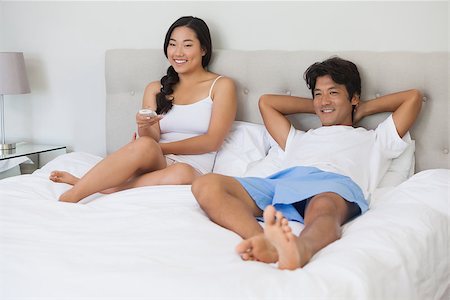 simsearch:400-07483522,k - Happy couple lying on bed together watching tv at home in bedroom Stock Photo - Budget Royalty-Free & Subscription, Code: 400-07483120