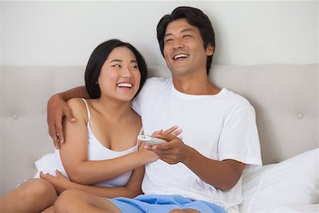 simsearch:400-07483522,k - Happy couple lying on bed together watching tv at home in bedroom Stock Photo - Budget Royalty-Free & Subscription, Code: 400-07483122