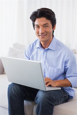 simsearch:400-07474252,k - Happy man sitting on couch using laptop at home in the living room Stock Photo - Budget Royalty-Free & Subscription, Code: 400-07483244