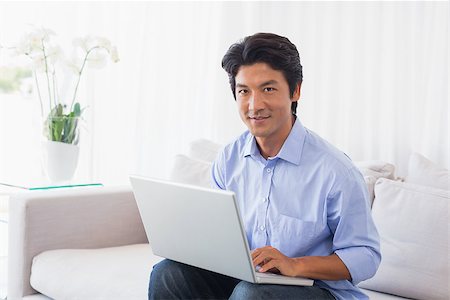 simsearch:400-07474252,k - Happy man sitting on couch using laptop at home in the living room Stock Photo - Budget Royalty-Free & Subscription, Code: 400-07483245