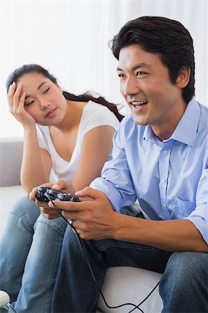 simsearch:400-07483384,k - Woman being ignored by boyfriend playing video games at home in the living room Stock Photo - Budget Royalty-Free & Subscription, Code: 400-07483271