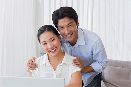 simsearch:400-07483384,k - Happy couple using laptop together at home in the living room Stock Photo - Budget Royalty-Free & Subscription, Code: 400-07483358