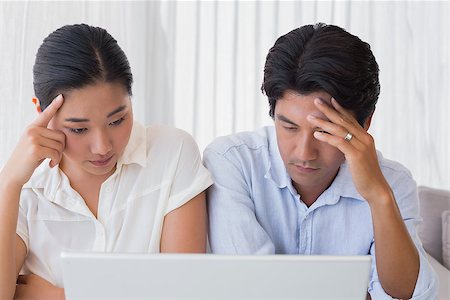 simsearch:400-07483384,k - Worried couple using laptop together at home in the living room Stock Photo - Budget Royalty-Free & Subscription, Code: 400-07483371