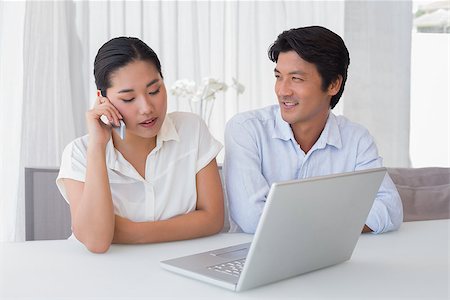 simsearch:400-07483384,k - Couple using laptop with woman talking on phone at home in the living room Stock Photo - Budget Royalty-Free & Subscription, Code: 400-07483372