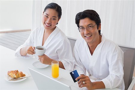 simsearch:400-07483384,k - Couple in bathrobes shopping online in the morning at home in the living room Stock Photo - Budget Royalty-Free & Subscription, Code: 400-07483384