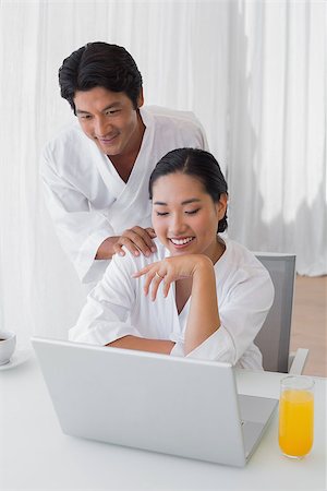 simsearch:400-07483384,k - Couple in bathrobes using laptop together in the morning at home in the living room Stock Photo - Budget Royalty-Free & Subscription, Code: 400-07483385