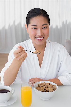 simsearch:400-07483384,k - Happy woman in bathrobe having her breakfast at home in the living room Stock Photo - Budget Royalty-Free & Subscription, Code: 400-07483391