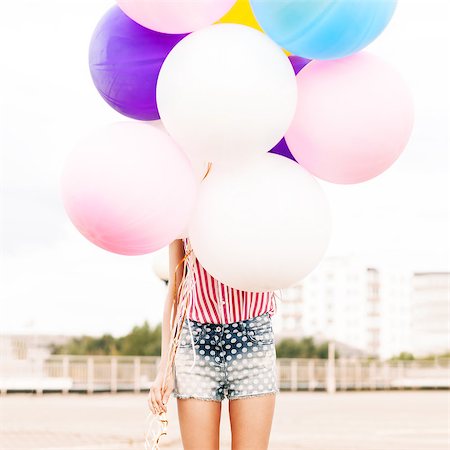 simsearch:400-07506274,k - close-up of girl in polka-dot short jeans shorts, sleeveless striped top hides in bunch of balloons Fotografie stock - Microstock e Abbonamento, Codice: 400-07506255