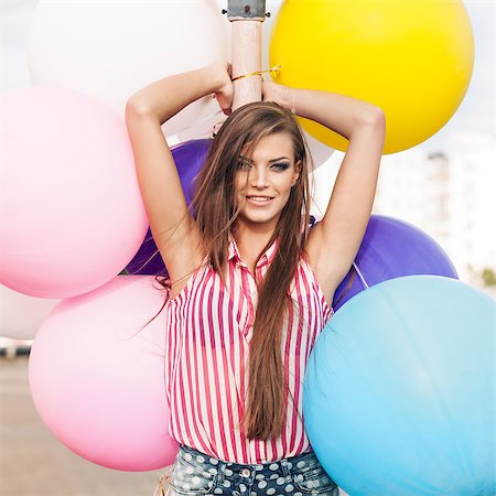 simsearch:400-07506274,k - young smiling girl with messy hair in short denim shorts and sleeveless striped top leans on light-pole holding bunch of bright balloons Photographie de stock - Aubaine LD & Abonnement, Code: 400-07506258