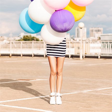 simsearch:400-07506274,k - girl in black and white striped short dress and white high top sneakers hides in bunch of multicolored balloons Fotografie stock - Microstock e Abbonamento, Codice: 400-07506271