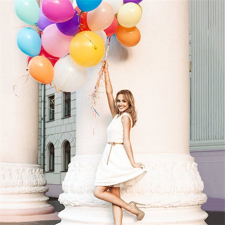 elio - pretty blonde smiling girl in white summer dress holds a bunch of multicolored balloons in front of old column Fotografie stock - Microstock e Abbonamento, Codice: 400-07506323