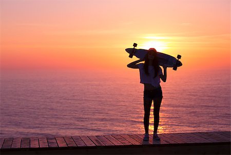 Beautiful girl holding a skateboard with the sunset in the background Stock Photo - Budget Royalty-Free & Subscription, Code: 400-07507525