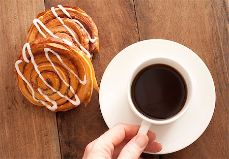 stockarch (artist) - Man reaching for a cup and saucer of full roast espresso coffee with fresh Danish pastries for a refreshing coffee break, high angle view on wood Foto de stock - Royalty-Free Super Valor e Assinatura, Número: 400-07507879