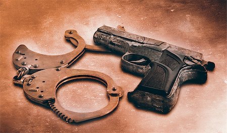 Gun and handcuffs on table. Photo in old color image style Stock Photo - Budget Royalty-Free & Subscription, Code: 400-07508565
