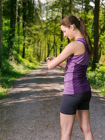 simsearch:400-07509642,k - Photo of a young woman on a jogging path through a forest checking her running time. Stock Photo - Budget Royalty-Free & Subscription, Code: 400-07509631