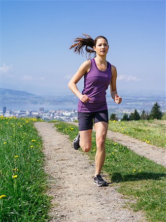 Photo of a young woman jogging and exercising on a country path.  Lake and city in the distance. Slight motion blur visible. Stock Photo - Budget Royalty-Free & Subscription, Code: 400-07509642