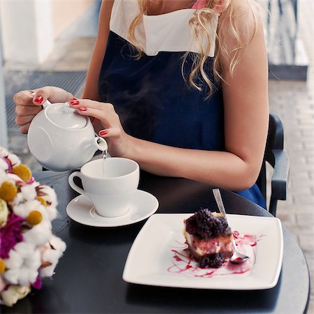a beautiful young blond girl with a happy toothy smile in summer dress at the table in pavement cafe is pouring green tea from the teapot into a white ceramic cup Stock Photo - Budget Royalty-Free & Subscription, Code: 400-07509915