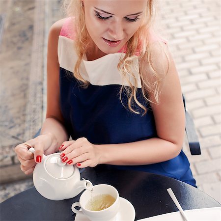 a beautiful young blond girl in summer dress at the table in pavement cafe is pouring green tea from the teapot into a white ceramic cup Stock Photo - Budget Royalty-Free & Subscription, Code: 400-07509916