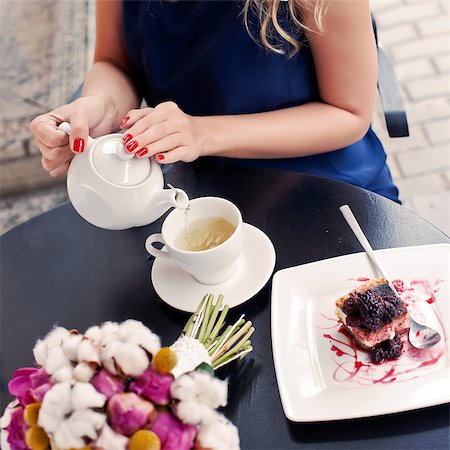 a beautiful young blond girl in summer dress at the table in pavement cafe is pouring green tea from the teapot into a white ceramic cup Stock Photo - Budget Royalty-Free & Subscription, Code: 400-07509917