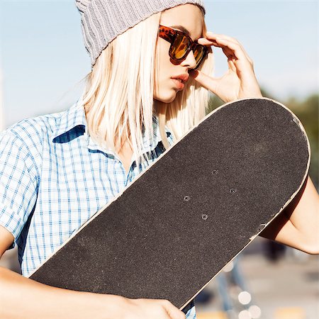simsearch:400-07506274,k - Close-up of beautiful blond girl in beanie hat skateboard adjusting her leopard sunglasses on sunny day in the street Fotografie stock - Microstock e Abbonamento, Codice: 400-07509955