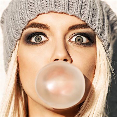 simsearch:400-07506274,k - Portrait of beautiful young blond girl in beanie hat blows big bubble from bubble gum Fotografie stock - Microstock e Abbonamento, Codice: 400-07509968