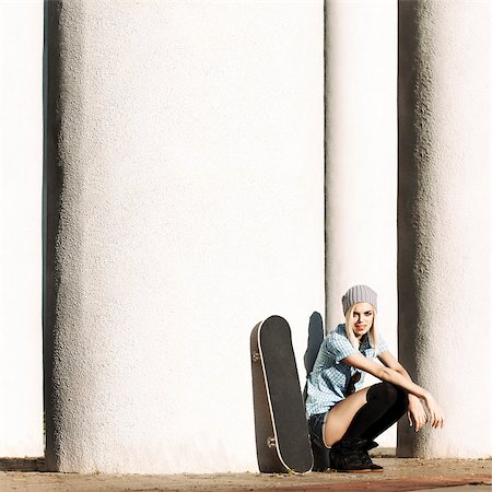 Beautiful girl in short shorts and stockings with skateboard sits on her haunches near  columns on sunny day Stock Photo - Budget Royalty-Free & Subscription, Code: 400-07509961