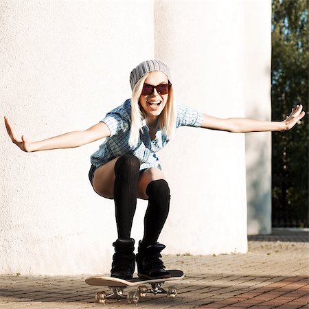 Beautiful smiling blond girl in sunglasses, shorts and stockings rides happily on skateboard Stock Photo - Budget Royalty-Free & Subscription, Code: 400-07509962