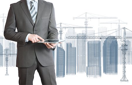 Businessman in suit hold tablet pc. Wire frame tower crane and skyscrapers on the background Stock Photo - Budget Royalty-Free & Subscription, Code: 400-07517734