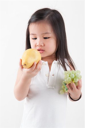 feed grapes - Child eats fruit. Little Asian girl eating pear and grapes, isolated on white background Stock Photo - Budget Royalty-Free & Subscription, Code: 400-07518981