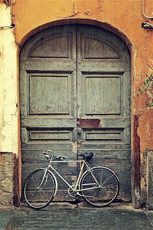 Vertical oriented image of bicycle leaning against old wooden door at the entrance to house on rainy day in Alba, Italy. Stock Photo - Budget Royalty-Free & Subscription, Code: 400-07511791