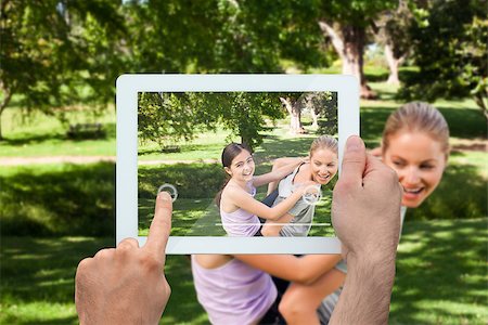 family with tablet in the park - Hand holding tablet pc showing mother giving her daughter a piggy back in park Photographie de stock - Aubaine LD & Abonnement, Code: 400-07512432