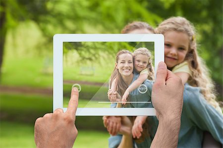 family with tablet in the park - Hand holding tablet pc showing mother giving daughter a piggy back Photographie de stock - Aubaine LD & Abonnement, Code: 400-07512453