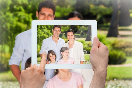 family with tablet in the park - Hand holding tablet pc showing family smiling at camera in park Photographie de stock - Aubaine LD & Abonnement, Code: 400-07512736