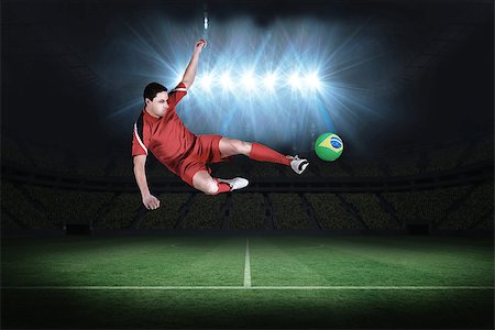 Fit football player jumping and kicking in a football pitch under spotlights Stock Photo - Budget Royalty-Free & Subscription, Code: 400-07525888