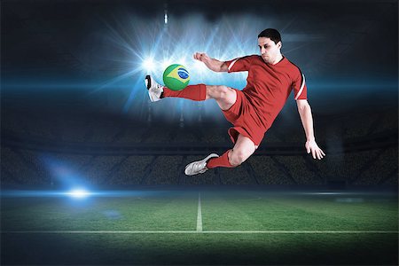 Fit football player jumping and kicking in a football pitch under spotlights Stock Photo - Budget Royalty-Free & Subscription, Code: 400-07525897