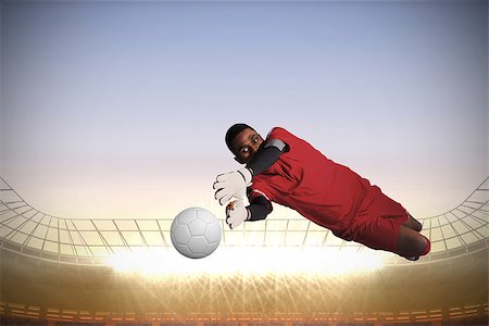 pale color sky - Goalkeeper in red making a save against large football stadium with spotlights Stock Photo - Budget Royalty-Free & Subscription, Code: 400-07526177