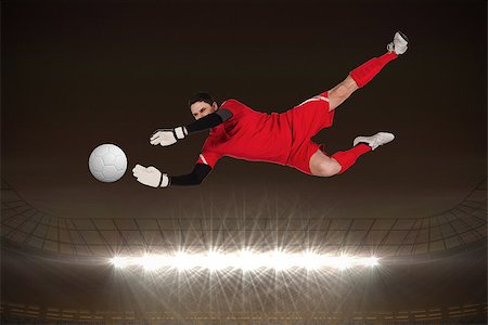 Fit goal keeper jumping up against large football stadium with spotlights at night Stock Photo - Budget Royalty-Free & Subscription, Code: 400-07526179