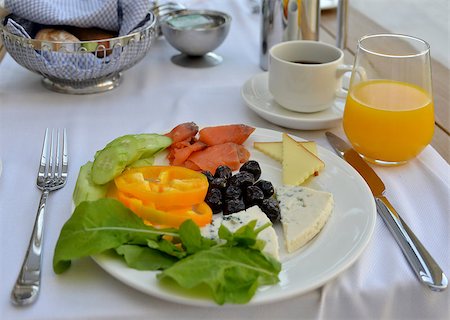 This is a breakfast with fresh vegetables, olives, coffee, orange juice, fish and cheese. The breakfast is served on the white dish. Fotografie stock - Microstock e Abbonamento, Codice: 400-07548645