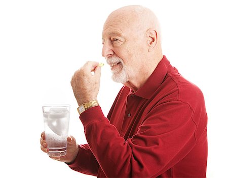 Handsome senior man stays healthy by taking a fish oil supplement with a glass of water.   Isolated on white. Stock Photo - Budget Royalty-Free & Subscription, Code: 400-07554284