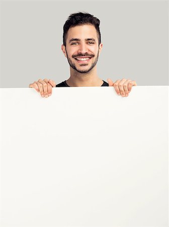 Beautiful latin man smiling and holding a blank billboard Stock Photo - Budget Royalty-Free & Subscription, Code: 400-07558114