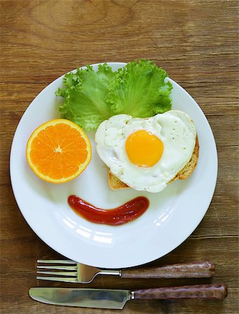 funny face serving breakfast, fried egg, toast and green salad Stock Photo - Budget Royalty-Free & Subscription, Code: 400-07558335