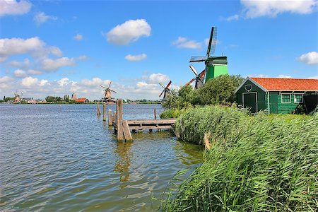 Wooden windmills along river under beautiful blue sky with white clouds in famous dutch village of Zaanse Schans. Stock Photo - Budget Royalty-Free & Subscription, Code: 400-07550787