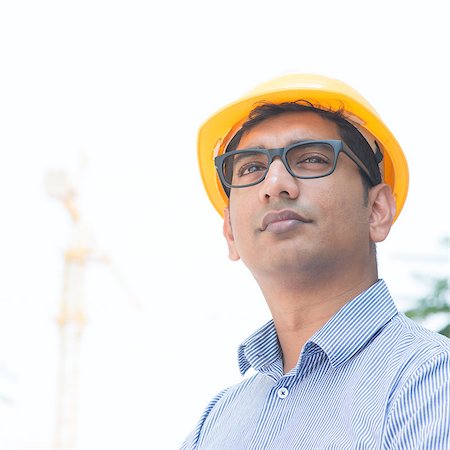 engineer background - Portrait of an Asian Indian engineer looking away, standing in front construction crane, inspecting the progress of project. Stock Photo - Budget Royalty-Free & Subscription, Code: 400-07553684