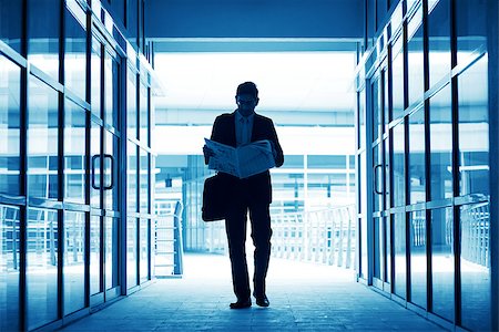 simsearch:400-07978342,k - Silhouette of business man residing newspaper and walking thru modern office building, in blue tone. Photographie de stock - Aubaine LD & Abonnement, Code: 400-07553689